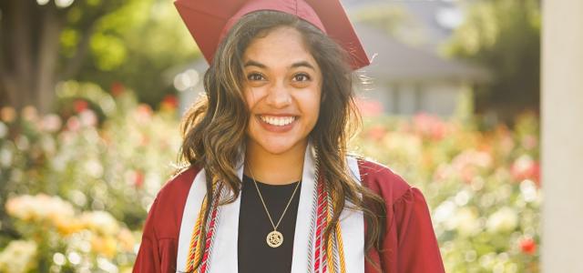 woman in red academic dress wearing red academic hat by Conner Ching courtesy of Unsplash.